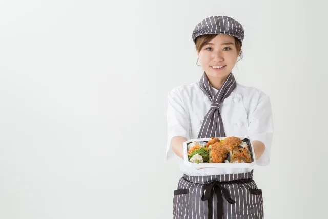 弁当を差し出す女性スタッフ