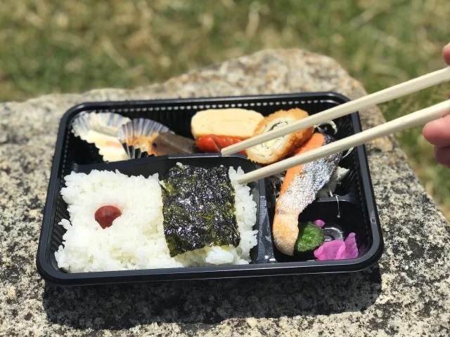 屋外で弁当を食べる人